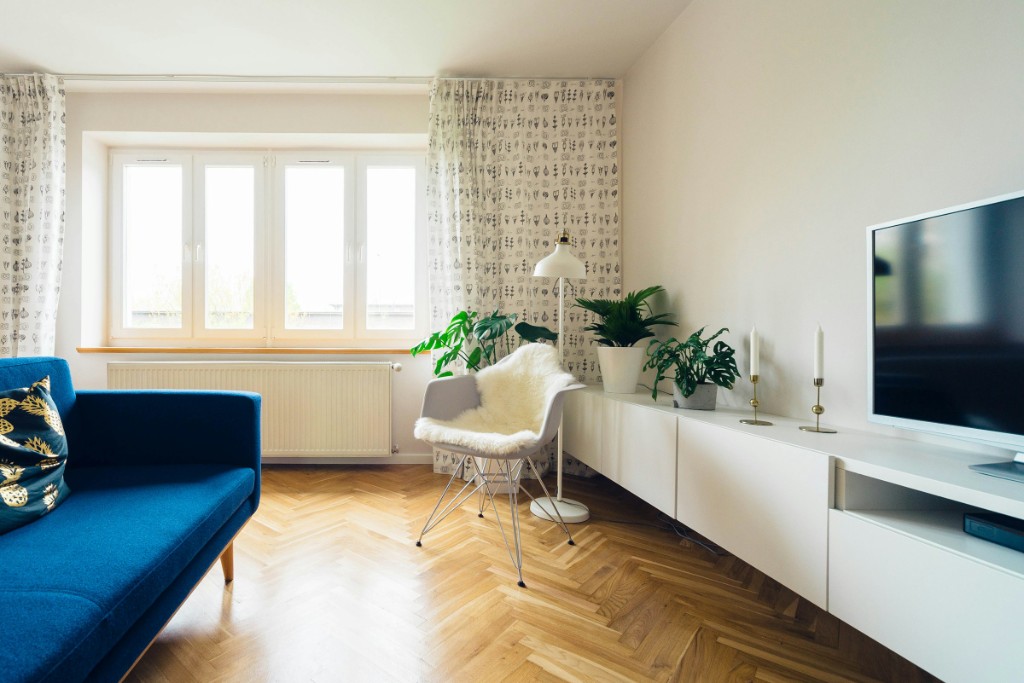 Bright living room with a blue sofa, white chair, and herringbone wood floor