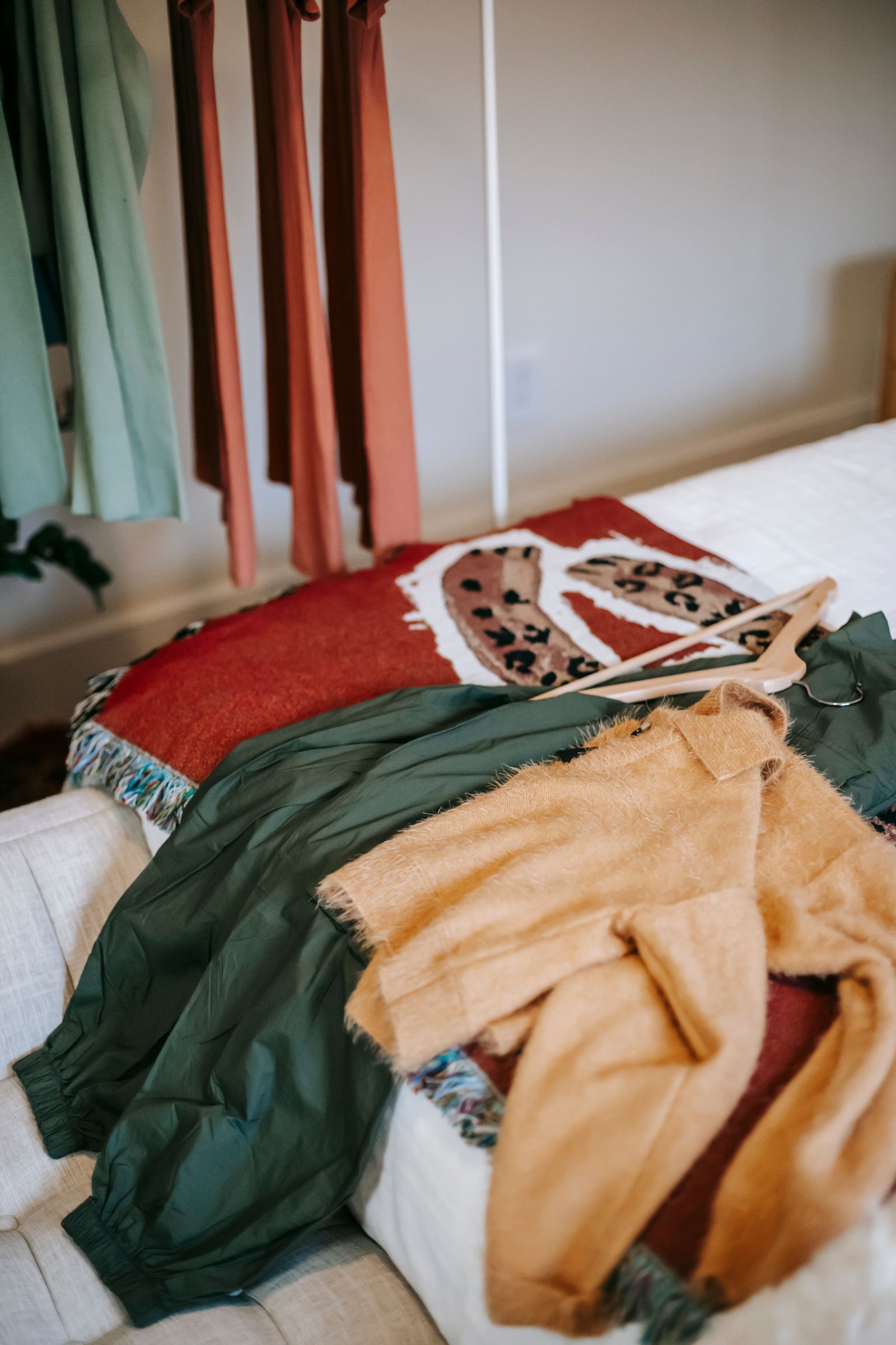 Jackets and sweaters laid out on a bed beside a wardrobe