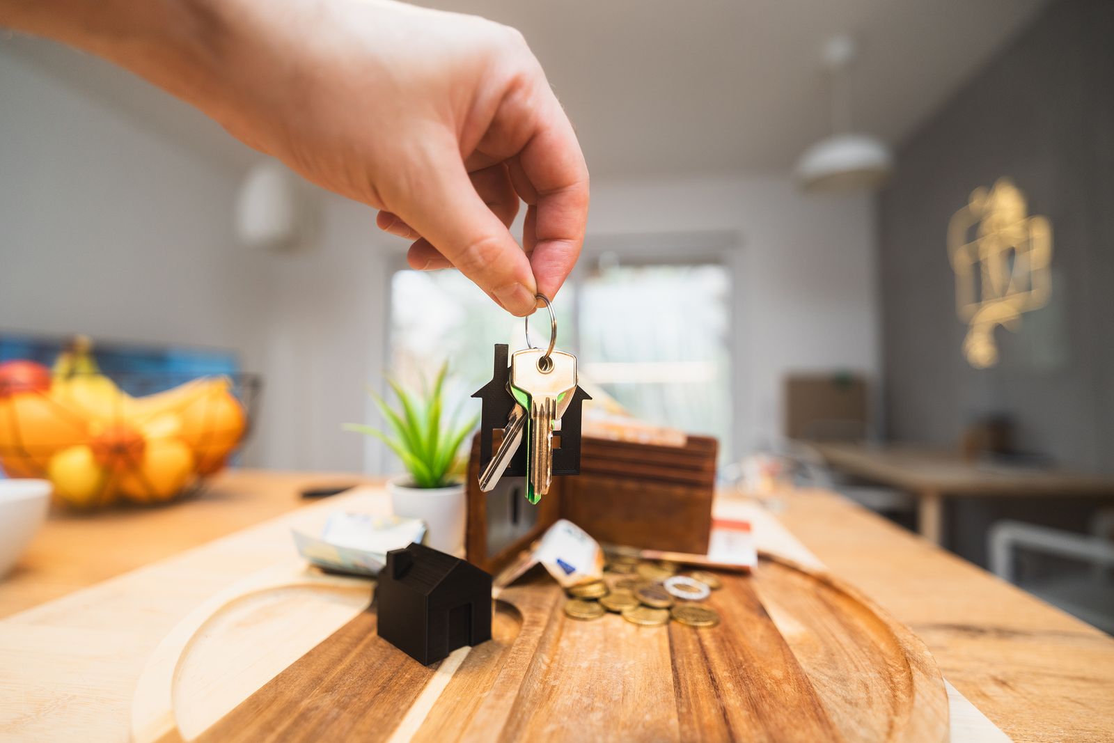 Hand holding house keys in a modern living room