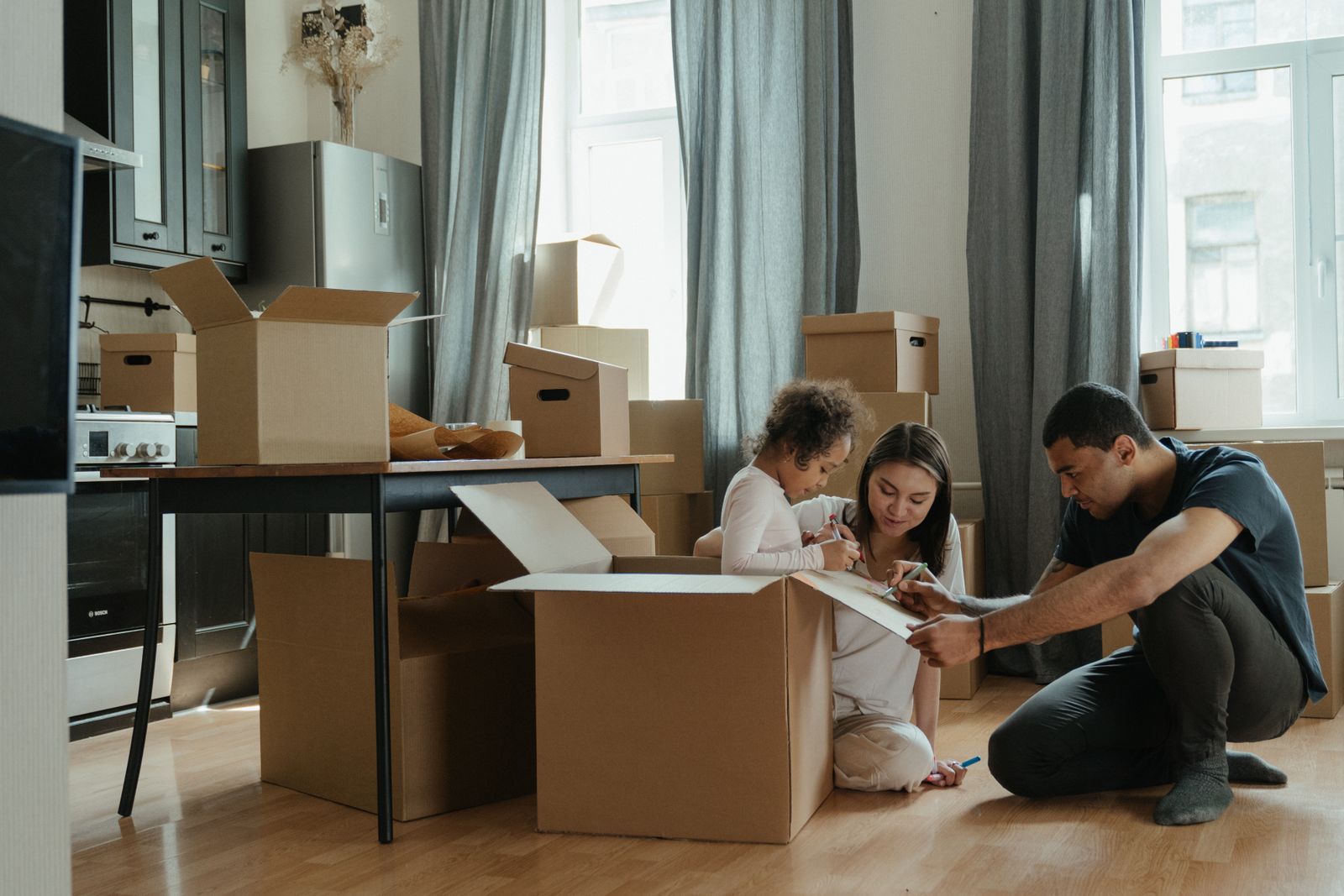 Family unpacking moving boxes in a kitchen