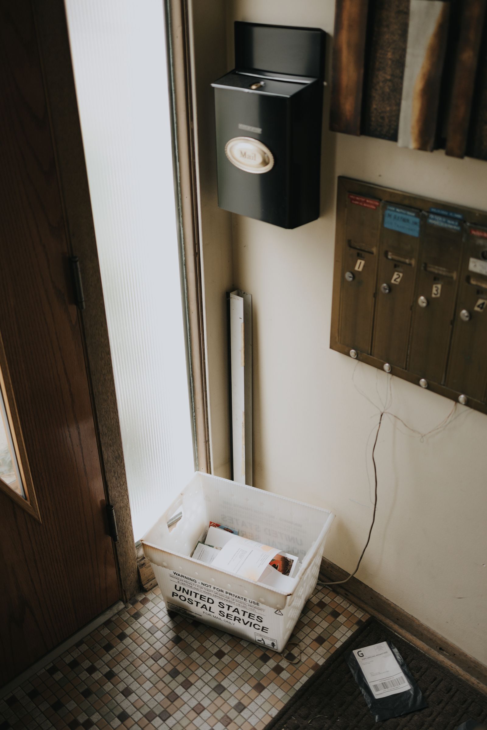 Apartment entry mailboxes with a parcel basket beside them