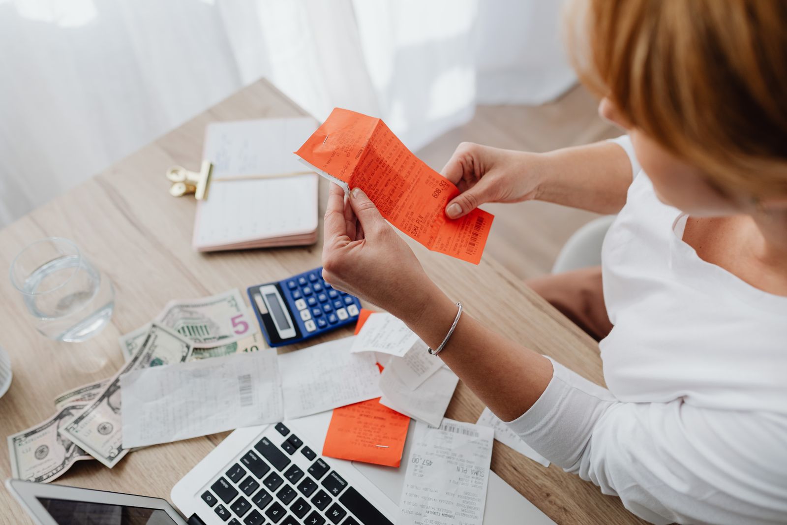 Person at a home desk sorting receipts with a calculator and papers
