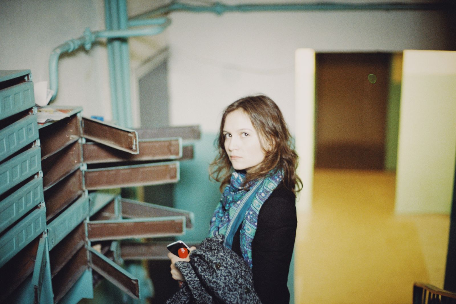 Person standing beside a row of mailboxes in an apartment stairwell