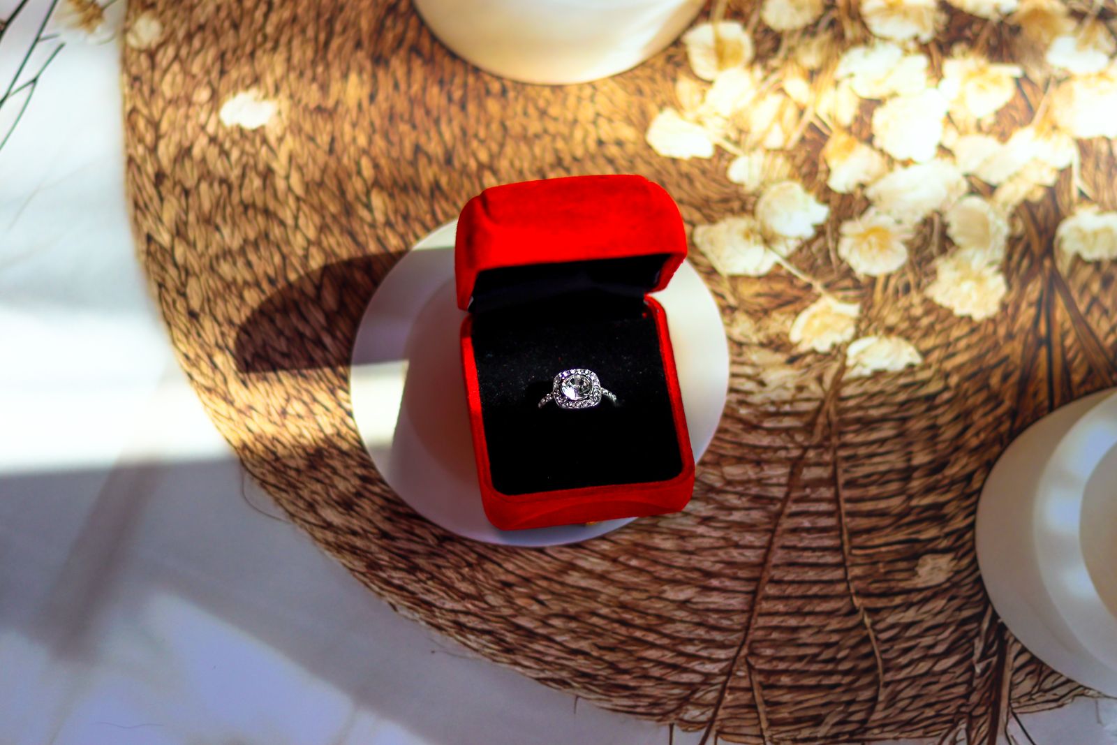 Diamond ring in an open red velvet box on a woven placemat