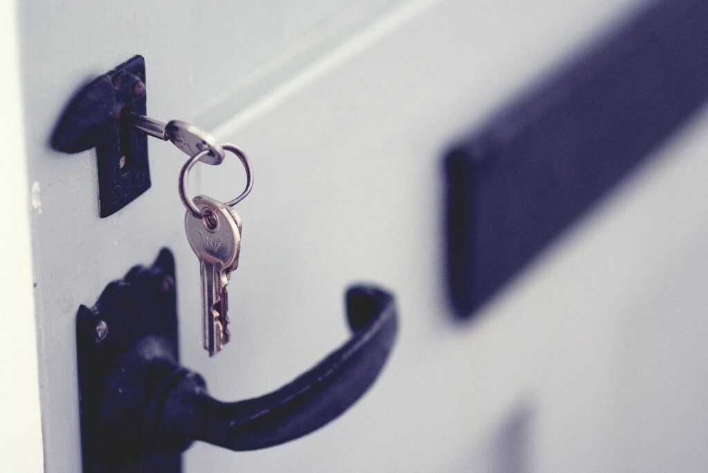 Keys on a ring hanging from a lock above a door handle