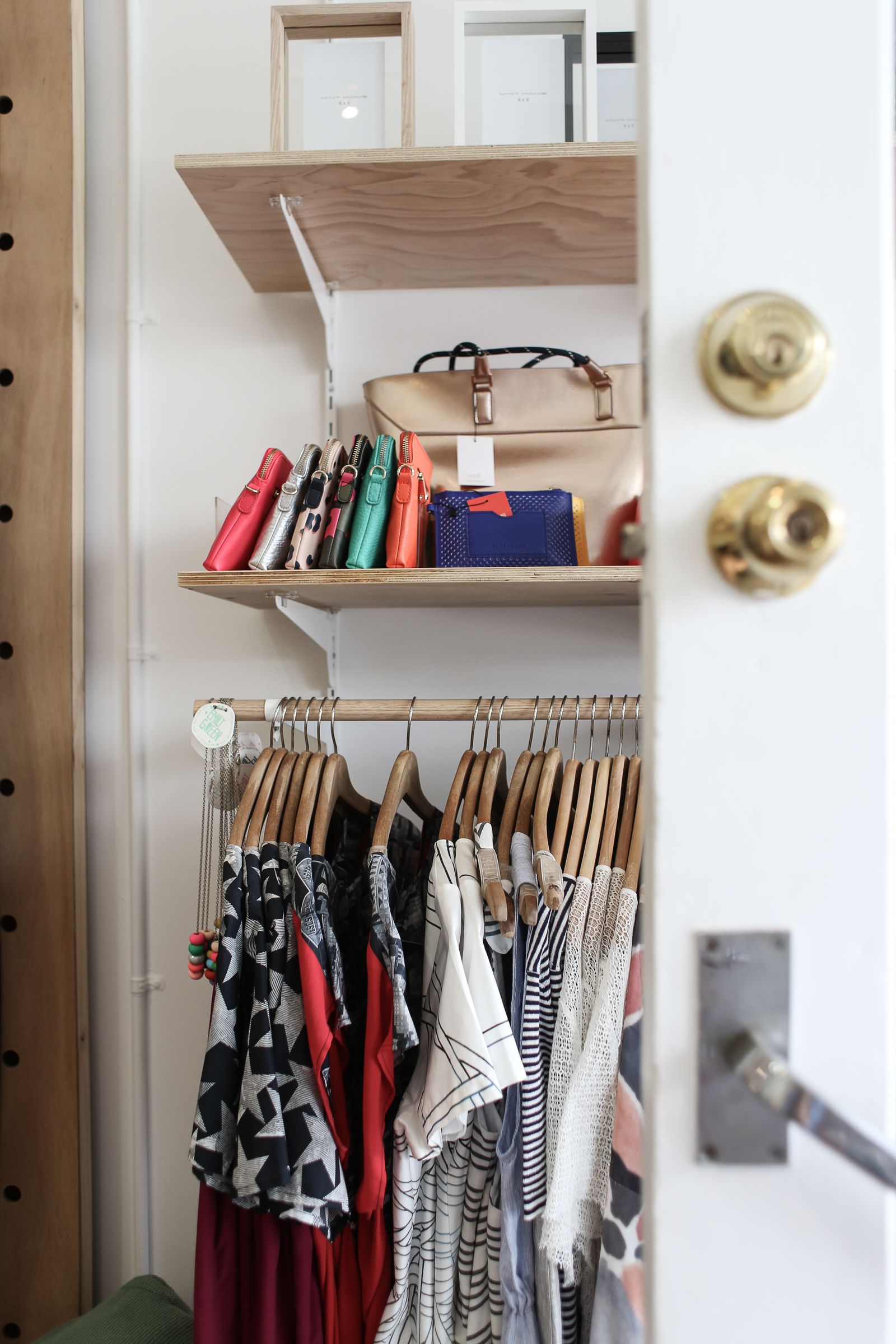 Organized closet with hanging clothes and handbags on shelves
