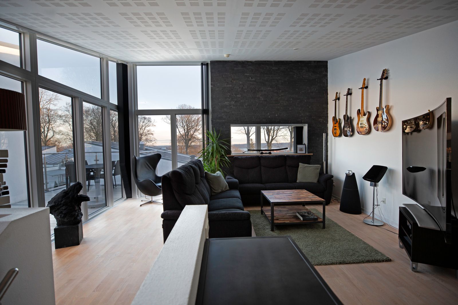 Living room with large windows and several guitars hanging on the wall