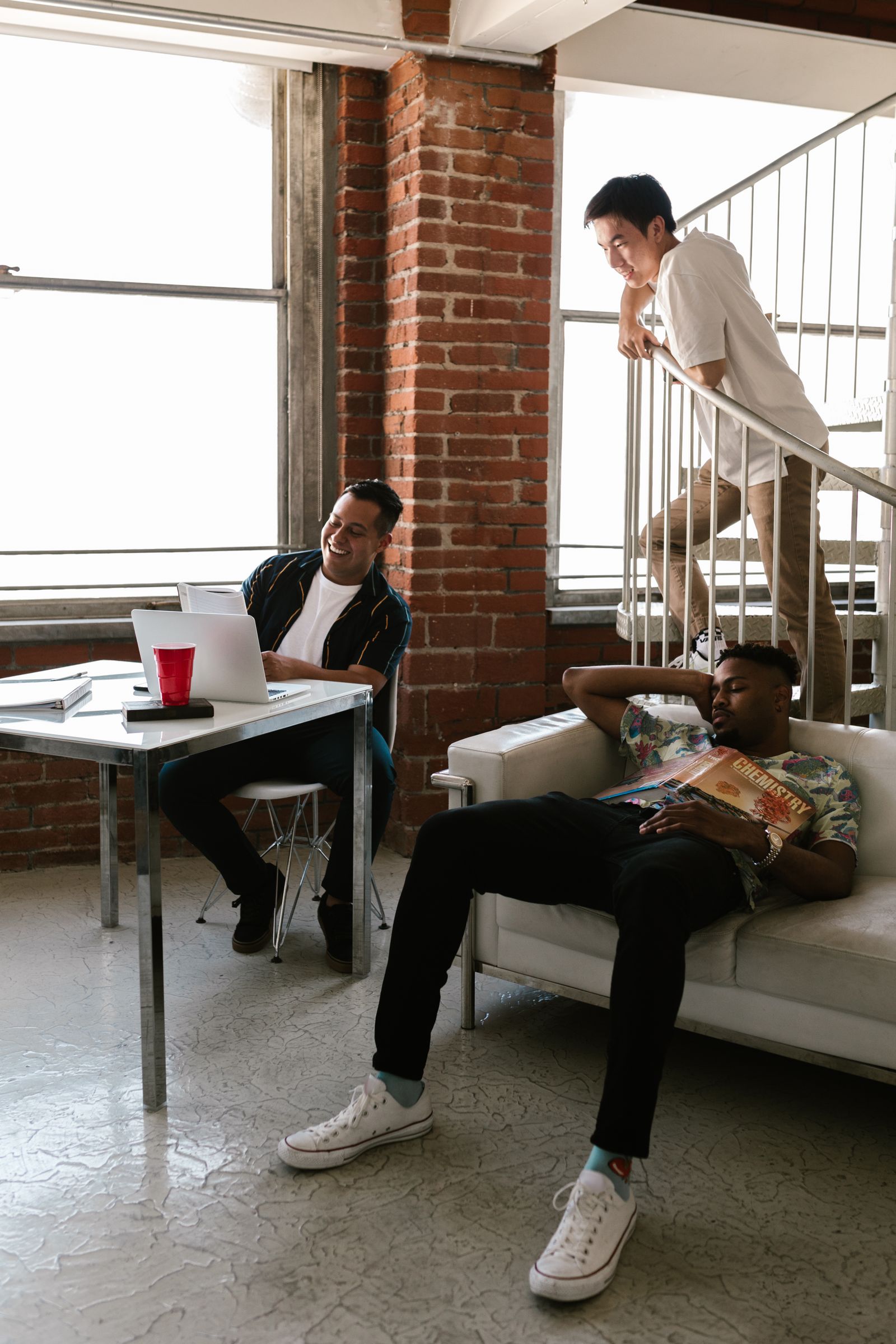 Young adults relaxing in a loft apartment with exposed brick and a spiral staircase