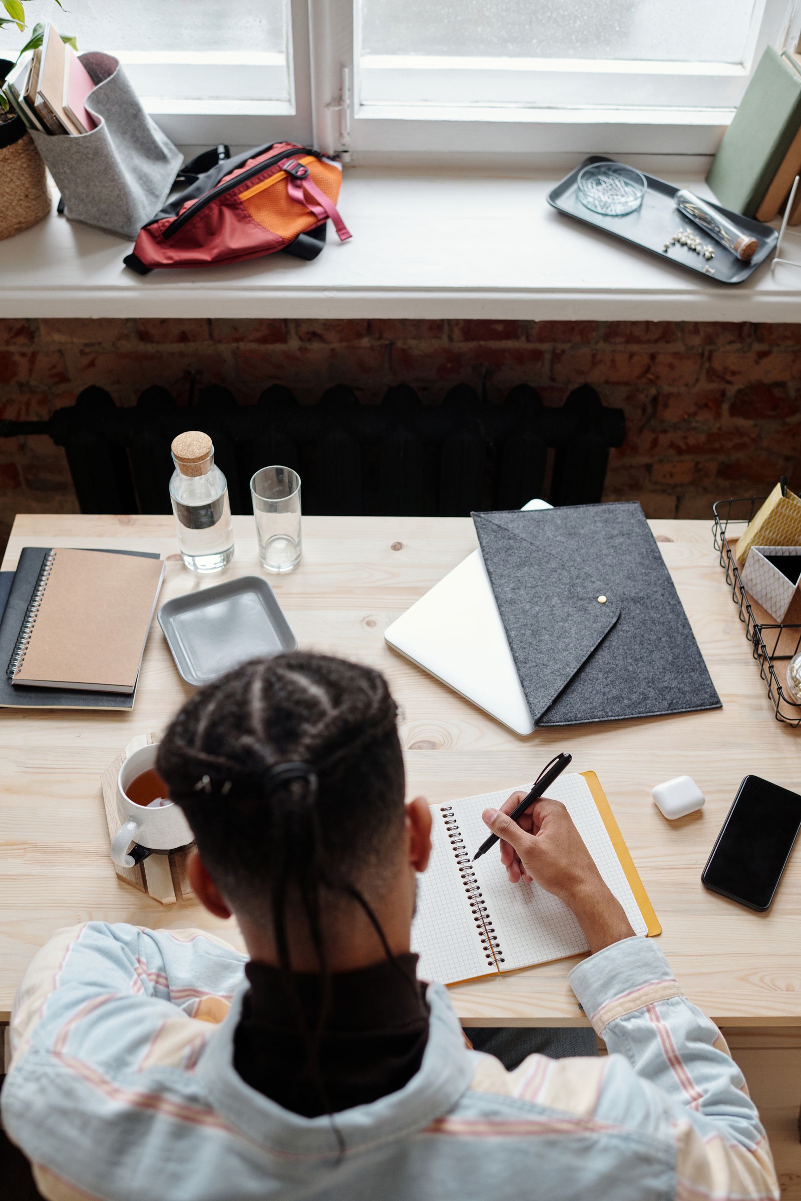Overhead view of a desk with notebooks, a phone, and a coffee cup