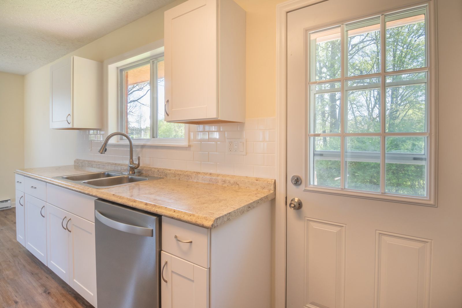 Sunlit kitchen with white cabinets and a sink under a window