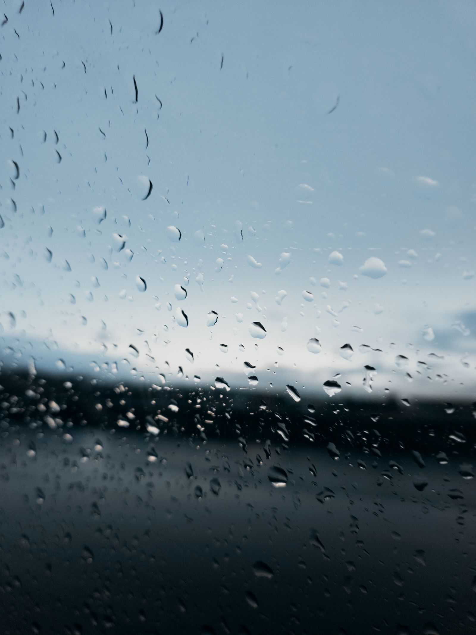 Raindrops on a window with a blurred view beyond the glass